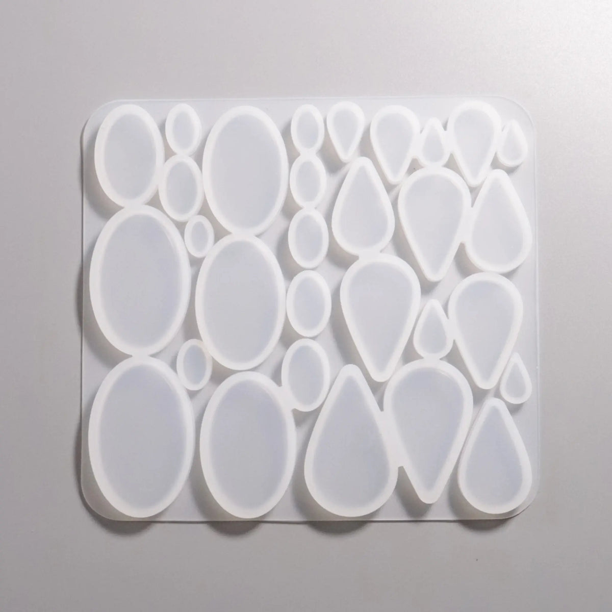 Silikon Gießformen verschieden große flache Ovale- und Tropfen-Formen von ca. 1 cm bis 5 cm. Darstellung Rückseite.