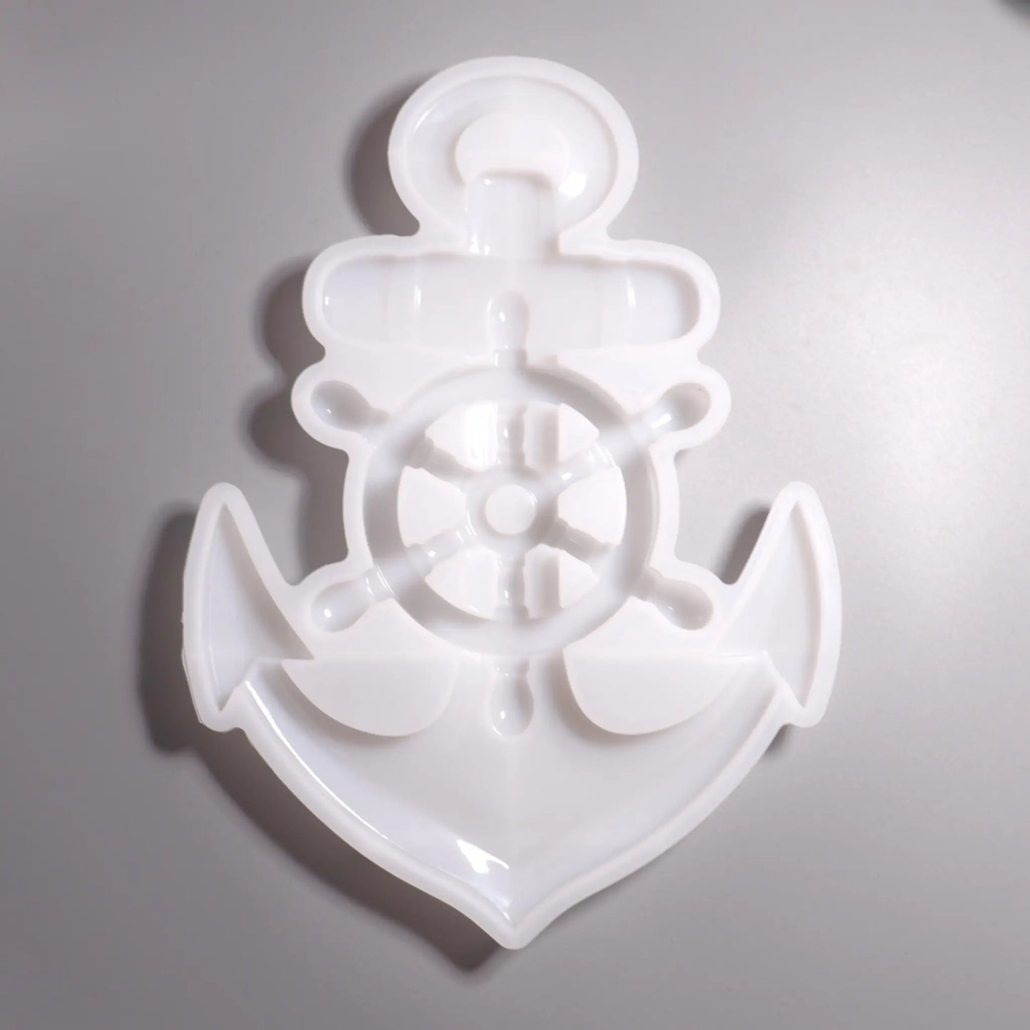 Weiße Silikon Gießform Anker mit Steuerrad Maritime Dekoration. Hintergrund grau. 