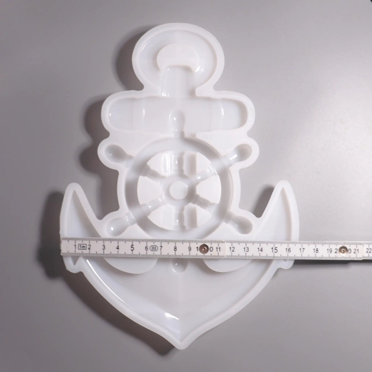 Weiße Silikon Gießform Anker mit Steuerrad Maritime Dekoration. Vorder Ansicht mit Lineal zu Ansicht. Hintergrund grau. 