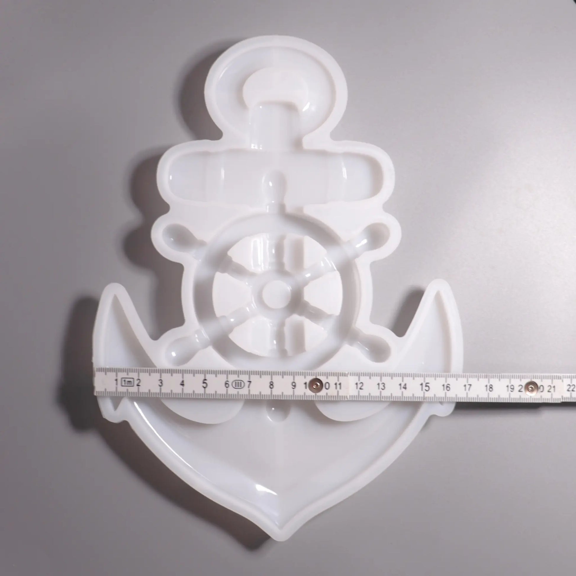Weiße Silikon Gießform Anker mit Steuerrad Maritime Dekoration. Vorder Ansicht mit Lineal zu Ansicht. Hintergrund grau. 