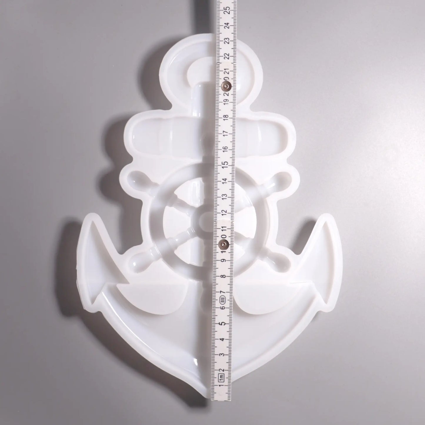 Weiße Silikon Gießform Anker mit Steuerrad Maritime Dekoration. Vorder Ansicht mit Lineal zu Ansicht. Hintergrund grau. 