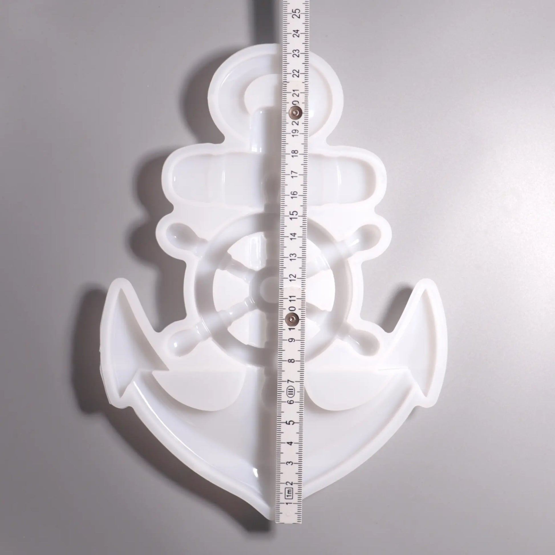 Weiße Silikon Gießform Anker mit Steuerrad Maritime Dekoration. Vorder Ansicht mit Lineal zu Ansicht. Hintergrund grau. 